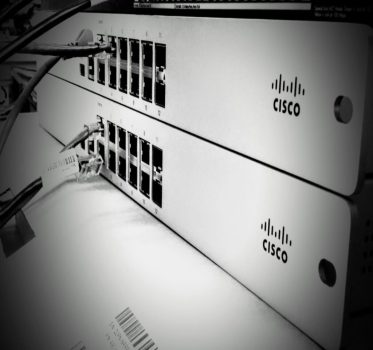 A black and white styled photo of 2 cisco network switches